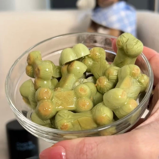A small glass bowl of frozen, green bone shaped dog treats flavored with mint.