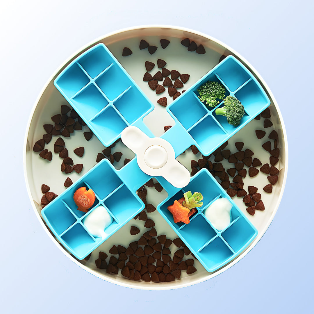 Spin bowl with a light blue, windmill-like inner section filled with vegetables nested into a white bowl filled with dog food.
