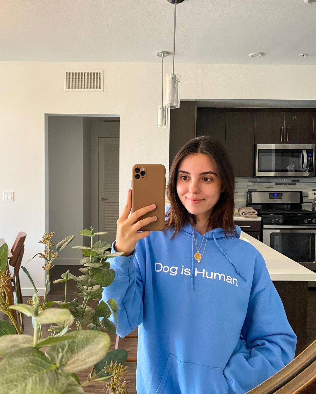 A young woman modeling a blue hoodie with Dog is Human branding on the chest.
